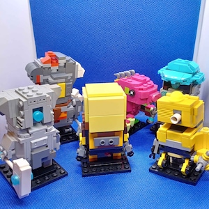 Pode incluir: Uma coleção de cinco pequenas figuras construídas com blocos sobre bases quadradas pretas. As figuras são feitas de peças de plástico cinzentas, amarelas, cor-de-rosa e azuis, com designs mecânicos que apresentam pinos e juntas visíveis.