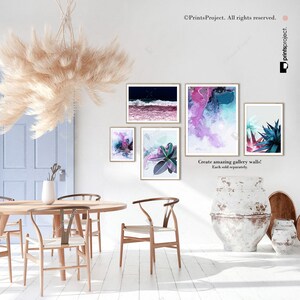May include: A set of four abstract art prints featuring a variety of colors and textures. The prints are displayed on a white wall in a dining room setting with a wooden table and chairs.