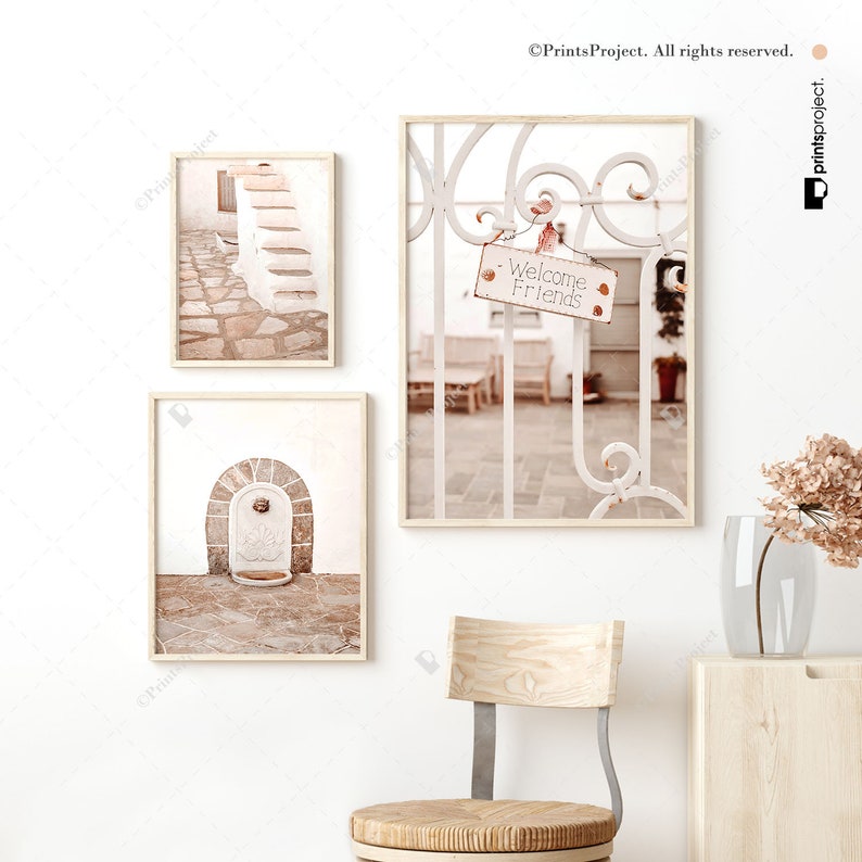 K&ouml;nnte beinhalten: Drei gerahmte Drucke mit wei&szlig;em Hintergrund und rustikalem, vintage-Look. Die Drucke zeigen einen Steinweg mit Treppen, einen wei&szlig;en Torbogen mit einem Steinbrunnen und ein wei&szlig;es Tor mit einem Schild, auf dem "Welcome Friends" steht.