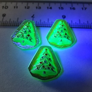 May include: Three green glass Christmas tree ornaments with gold and red details. The ornaments are in the shape of a triangle and have a raised design of a Christmas tree.