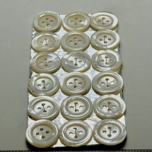 Een originele kaart met 18 antieke handgesneden iriserende, breed omrande witte dweilknoppen 7/8" #670