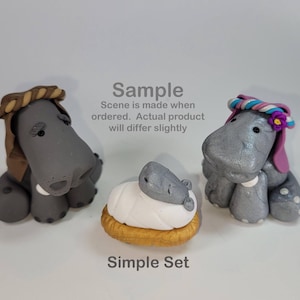 May include: A simple set of handmade clay hippos. Two gray hippos are adorned with headwear, and a baby hippo rests on a white and gold base. The text "Sample" and "Simple Set" are visible.