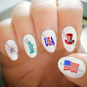 Peut inclure: Ensemble de cinq autocollants pour ongles sur le thème patriotique américain. Les autocollants comprennent un motif de feux d'artifice rouge, blanc et bleu, une Statue de la Liberté verte, le mot "USA" en lettres bleues et rouges, un chapeau d'Oncle Sam rouge, blanc et bleu et un drapeau américain rouge, blanc et bleu.