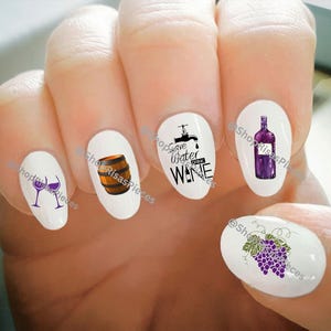 Peut inclure: Ensemble de six autocollants pour ongles sur le thème du vin avec une bouteille de vin, un verre à vin, un tonneau, des raisins et un robinet avec le texte "Save Water Drink Wine".