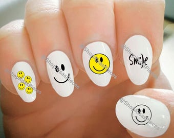 May include: Yellow smiley face nail decals with black outlines. The decals are on a white background and are arranged in a row on a hand. The decals are for nail art and are sold in a set of 10.
