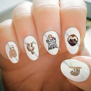 May include: Set of five sloth nail decals. The decals feature sloths in various poses, including hanging from a branch, holding a heart, and sleeping. One decal features the text "Sloth is the Slowest Animal".