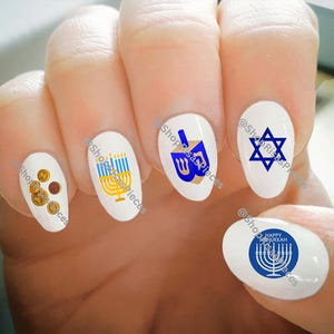May include: Set of six oval-shaped nail decals with a Hanukkah theme. The decals feature a menorah, dreidel, Star of David, and the words "Happy Hanukkah".