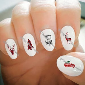 May include: Set of five Christmas themed nail decals. The decals feature a red and black plaid Christmas tree, a red and black plaid reindeer, a red pickup truck with a Christmas tree in the bed, and the text "merry and bright".
