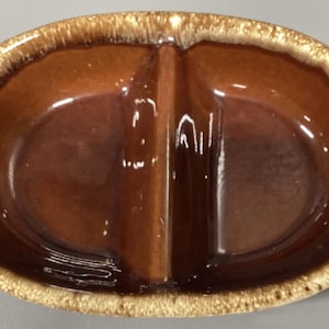 May include: A brown and white divided ceramic dish with a glazed finish. The dish has two sections and a raised divider in the center.