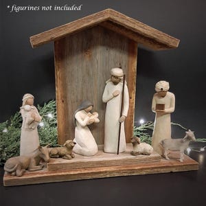 May include: A rustic wooden nativity scene with a gray, weathered finish. The scene features a manger with a roof, and figures of Mary, Joseph, and the baby Jesus. There are also figures of a donkey, a sheep, and a goat. The text "*figurines not included" is visible in the top left corner of the image.
