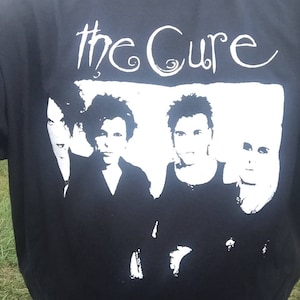May include: Black t-shirt with a white print of the band "The Cure" and a black and white image of the band members.