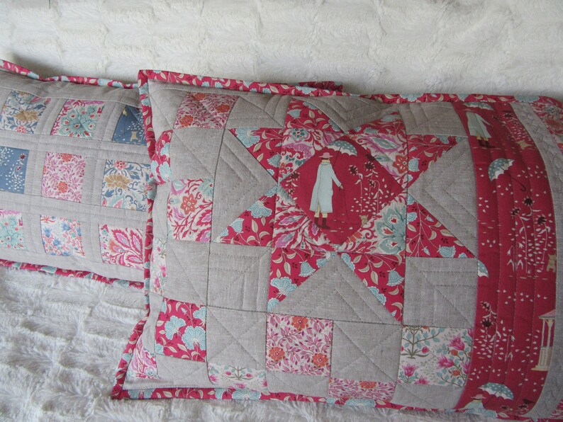May include: Two decorative pillow covers with a patchwork design. The pillow covers are made of a variety of fabrics, including linen and cotton. The pillow covers feature a star design and a floral pattern. The pillow covers are in shades of pink, red, and gray.