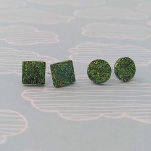 May include: A set of three green glitter earrings, two square and one round.