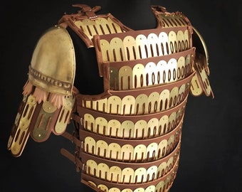 May include: A gold and brown leather cuirass with a scale mail design. The cuirass is displayed on a mannequin. The cuirass is made by Lykia Armour.