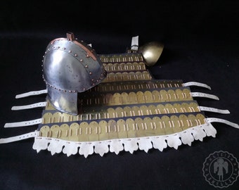 May include: A piece of historical armor, featuring a polished metal helmet and chest plate. The chest plate is constructed from overlapping brass-colored metal plates, secured with leather straps. The armor is designed with a curved shape and detailed rivets.
