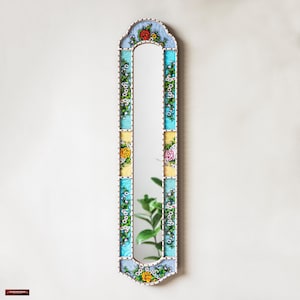 May include: A tall, rectangular mirror with a decorative frame. The frame is made of wood and painted in a light blue, yellow, and white color scheme. The frame is decorated with floral designs in shades of pink, yellow, and green.