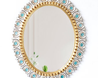 May include: An oval mirror with a gold and silver frame. The frame is decorated with turquoise blue accents.