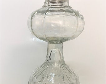 May include: A clear glass oil lamp with a round, ribbed globe and a fluted base.