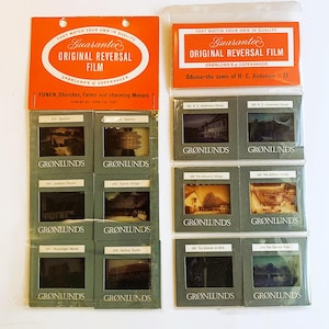 Op de afbeelding: Een verzameling vintage Grønlunds Original Reversal Film dia's, met afbeeldingen van Funen, kerken, boerderijen en herenhuizen. De dia's zijn verpakt in oranje en transparante plastic houders, met de tekst "Guarantee Original Reversal Film."