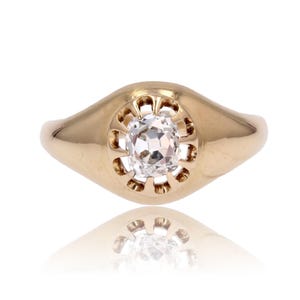 May include: A gold ring with a round, clear stone set in a decorative, openwork design.