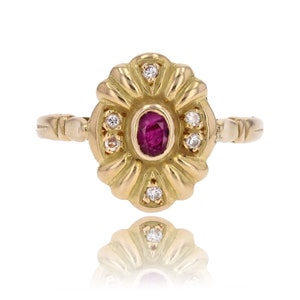 May include: A gold ring featuring a red ruby and small diamonds set in a floral design.