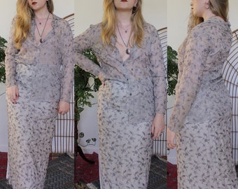 May include: A sheer, long-sleeved blouse and matching skirt set in a light gray color with a floral pattern. The set is made of a lightweight fabric and has a relaxed fit.