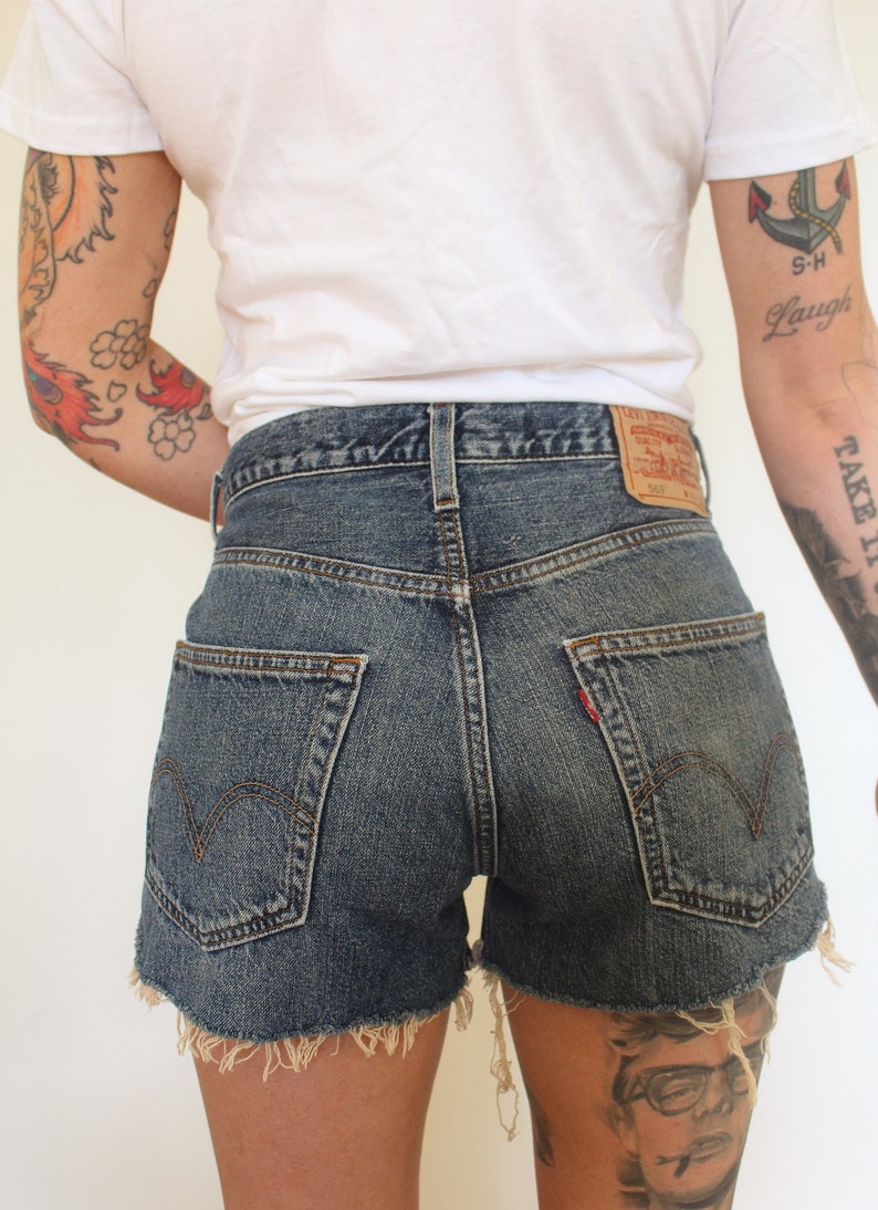 May include: A pair of blue denim shorts with frayed edges. The shorts have a classic five-pocket design and a Levi's patch on the back.