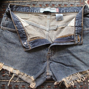 May include: Light blue denim shorts with frayed edges and a button and zipper closure. The shorts have a "Loose Straight" label on the waistband.