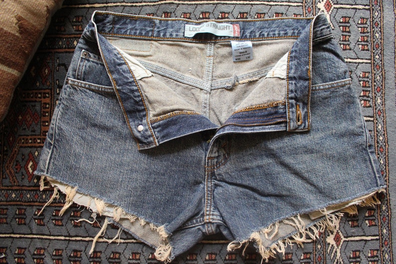 May include: Light blue denim shorts with frayed edges and a button and zipper closure. The shorts have a "Loose Straight" label on the waistband.