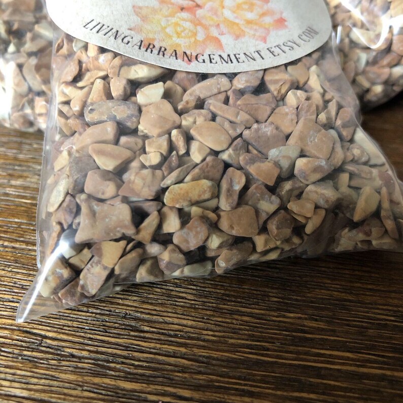May include: A clear plastic bag filled with small, irregular-shaped brown and beige stones. The bag is labeled "LivingArrangementEtsy.com".