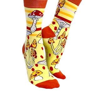 May include: A pair of yellow and orange socks with a pattern of pizza slice mushrooms. The socks have red polka dots and a white stripe.