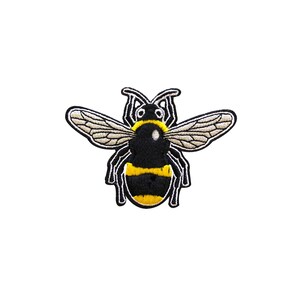 Puede incluir: Un parche bordado de abeja negro y amarillo con alas marrones.