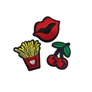 May include: Three embroidered iron-on patches: a red lip, a yellow and red french fry container, and a red cherry with a green stem.