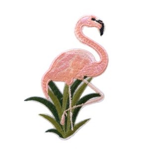 Op de afbeelding: Geborduurde patch met een roze flamingo op groene bladeren. De flamingo staat op één poot met zijn kop naar de zijkant gedraaid. De patch is perfect om kleding, tassen of andere accessoires een tropische touch te geven.