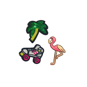 May include: Three iron-on patches: a pink flamingo, a green palm tree with yellow trunk, and a black and white roller skate with pink wheels.