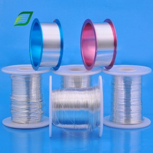 May include: Five spools of silver wire, each wound around a white plastic spool. Two spools are on a blue surface, and three spools are on a light blue surface. The spools are arranged in a row, with the two spools on the blue surface in the front.
