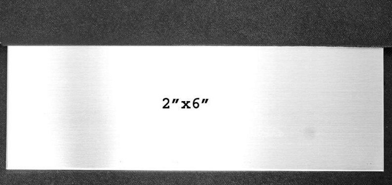 May include: A 2 inch by 6 inch blank metal plate. The plate is silver and has a brushed finish.
