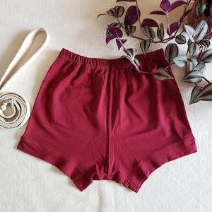 May include: A pair of burgundy cotton shorts with a wide waistband and a relaxed fit.