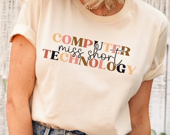 May include: A beige t-shirt with the text "COMPUTER miss short TECHNOLOGY" in colorful block letters.