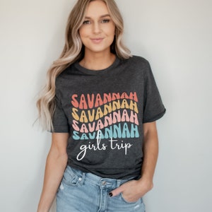 May include: A dark gray t-shirt with a rainbow design that says "Savannah girls trip" in a retro font.