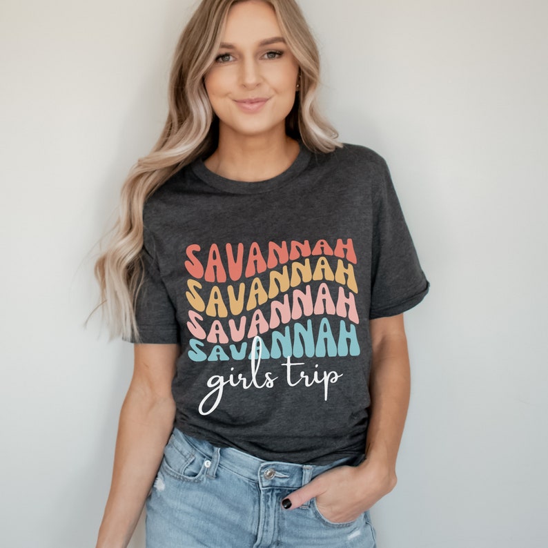 May include: A dark gray t-shirt with a rainbow design that says "Savannah girls trip" in a retro font.
