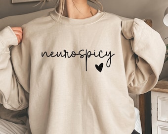 May include: A beige sweatshirt with the text "neurospicy" in black lettering and a small black heart.