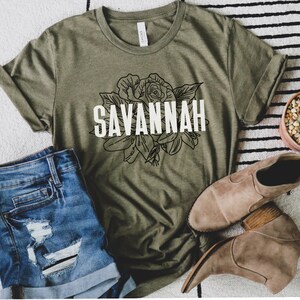 May include: A green t-shirt with a black and white floral design and the word "SAVANNAH" in white text.