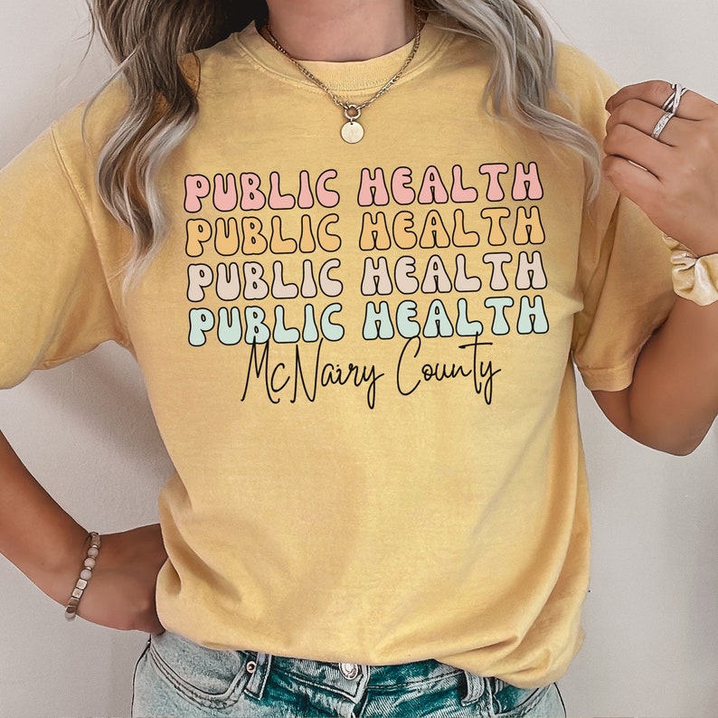 May include: Yellow t-shirt with the words "PUBLIC HEALTH" stacked four times in a retro font, with the words "McNairy County" below. The text is in pink, orange, light blue, and black.