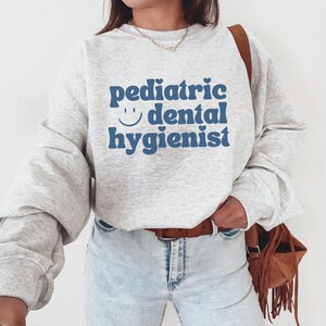 May include: A gray sweatshirt with the text "pediatric dental hygienist" in blue with a smiley face.