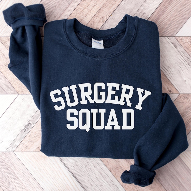 May include: A navy blue sweatshirt with the text "SURGERY SQUAD" in white.