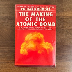 May include: A hardcover book titled "THE MAKING OF THE ATOMIC BOMB" by Richard Rhodes. The book cover is predominantly red with white text and a yellow and orange illustration. The text includes "WINNER OF THE 1987 NATIONAL BOOK AWARD".