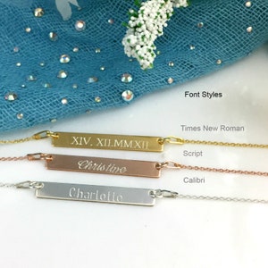 Puede incluir: Tres collares personalizados con barras en oro, oro rosa y plata. El collar de oro tiene números romanos, el collar de oro rosa dice "Christine" en cursiva, y el collar de plata dice "Charlotte" en Calibri. El texto "Font Styles" es visible.