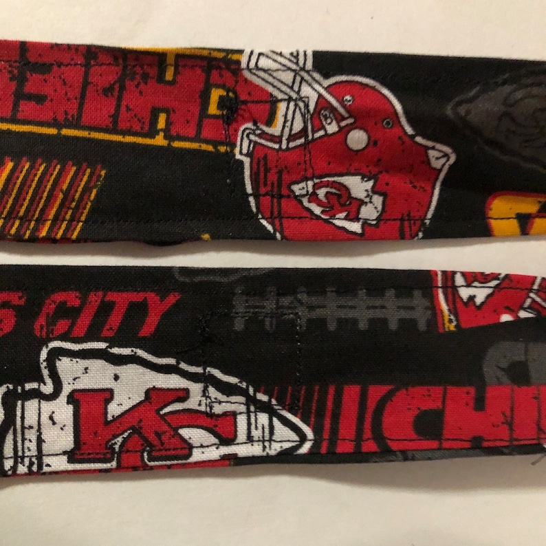 May include: Black and red fabric with a Kansas City Chiefs logo, the words "City" and "Chiefs", and a football helmet. The fabric has a distressed look.