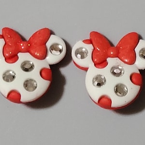 May include: Two red and white Minnie Mouse head-shaped buttons with rhinestones.